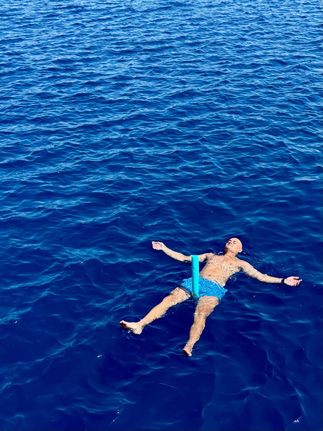 Una persona che galleggia sul dorso in mare aperto, a braccia aperte